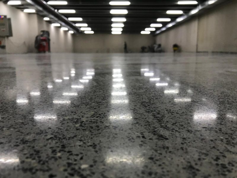 Aydınlatmayı yansıtan tam parlak beton zemin, geniş üretim holü