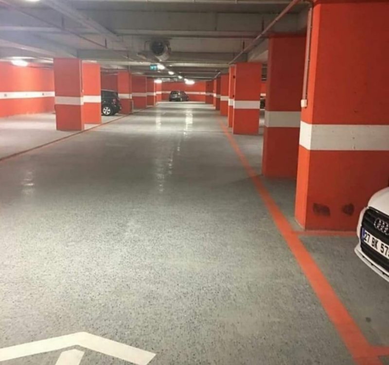Otopark katında yarı mat beton zemin, kırmızı kolonlu bölüm