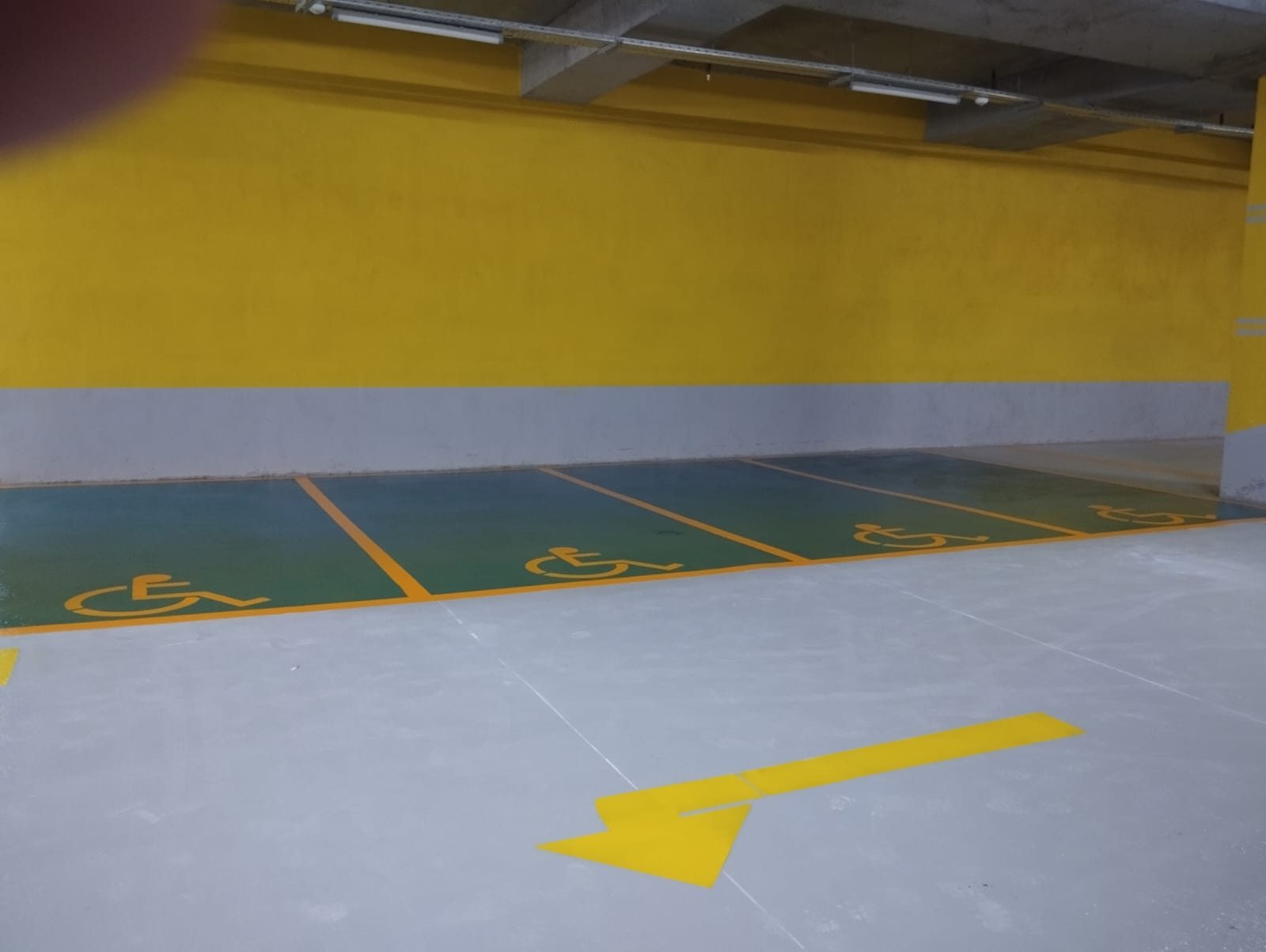 Otoparkta sarı yön oku ve engelli park yeri işaretlemesi